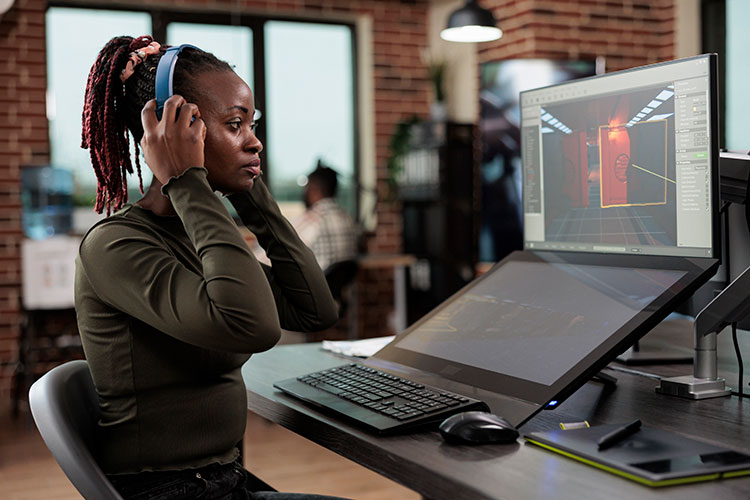 Une femme devant un ordinateur et des écouteurs aux oreilles pour illustrer un métier du numérique dans le cadre des astuces emploi